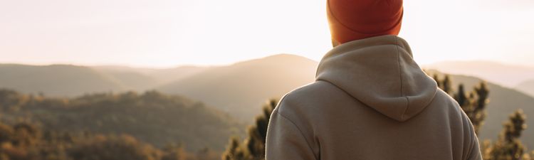 Rear view of man with knit hat in mountain peak at sunset