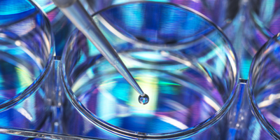 A pipette dispenses liquid into a multicolored multiwell plate.