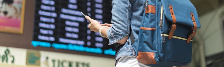 Medium angle of young woman checking timetable board in bus or train station.