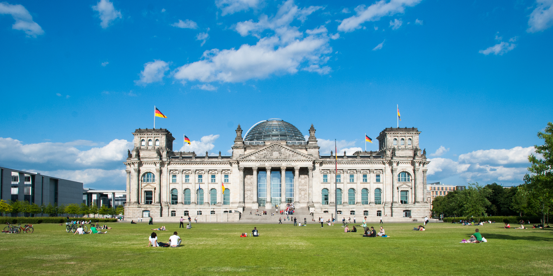 Berlin, Germany. The Reichstag, german parliament building visible from the 'Platz der Republik' with people relaxing on the grass in a summer day