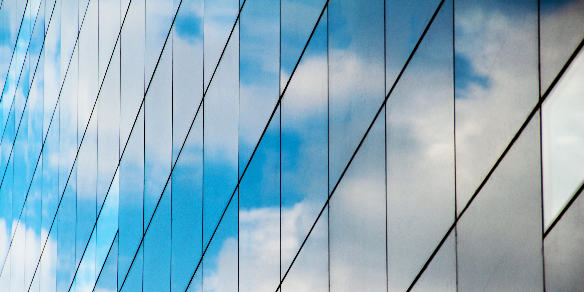 A reflection of clouds and sky in a mirrored glass building.