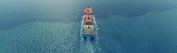 Aerial of container ship moving across an ocean.