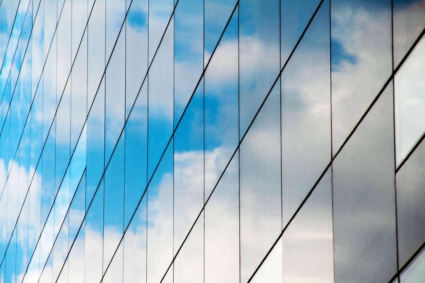 A reflection of clouds and sky in a mirrored glass building.