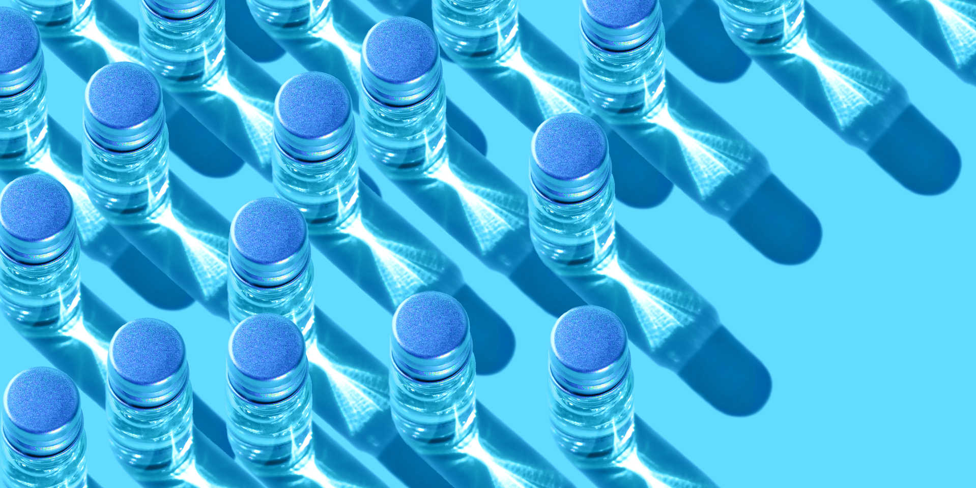 Overhead angle of metal-lidded glass vials containing clearly liquid.