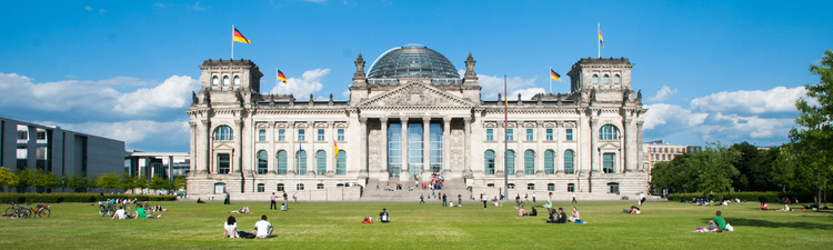 Berlin, Germany. The Reichstag, german parliament building visible from the 'Platz der Republik' with people relaxing on the grass in a summer day