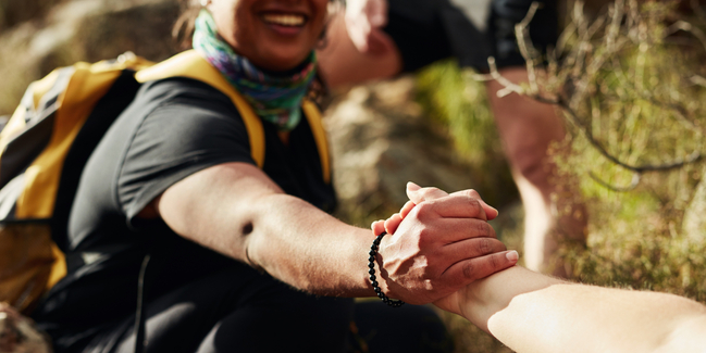 Medium angle of two people interlinking hands on hiking trail.