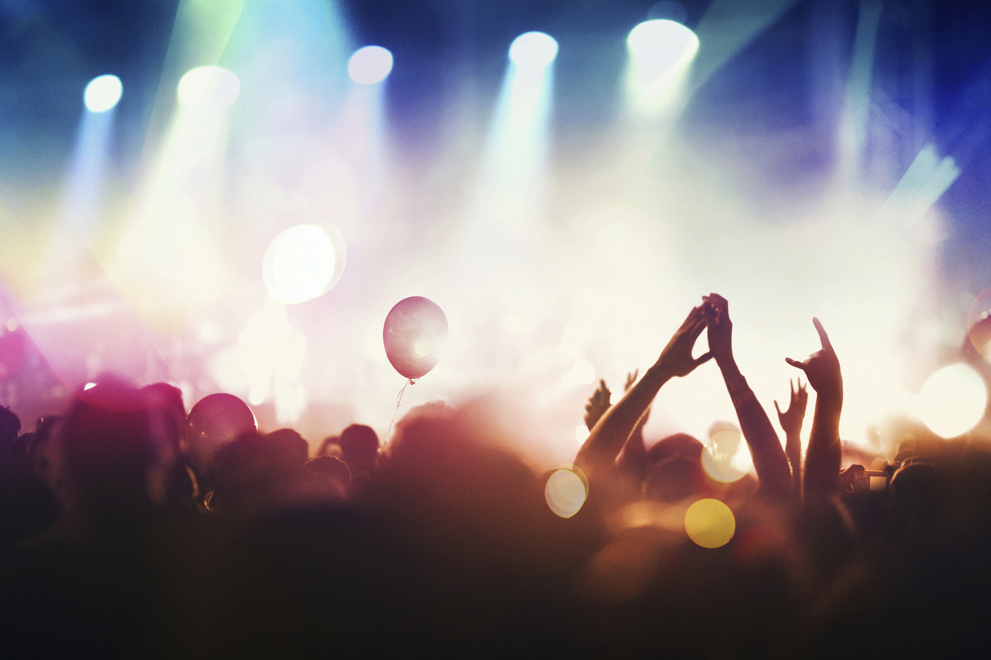 Medium angle of people with hands in the air at concert or live event.