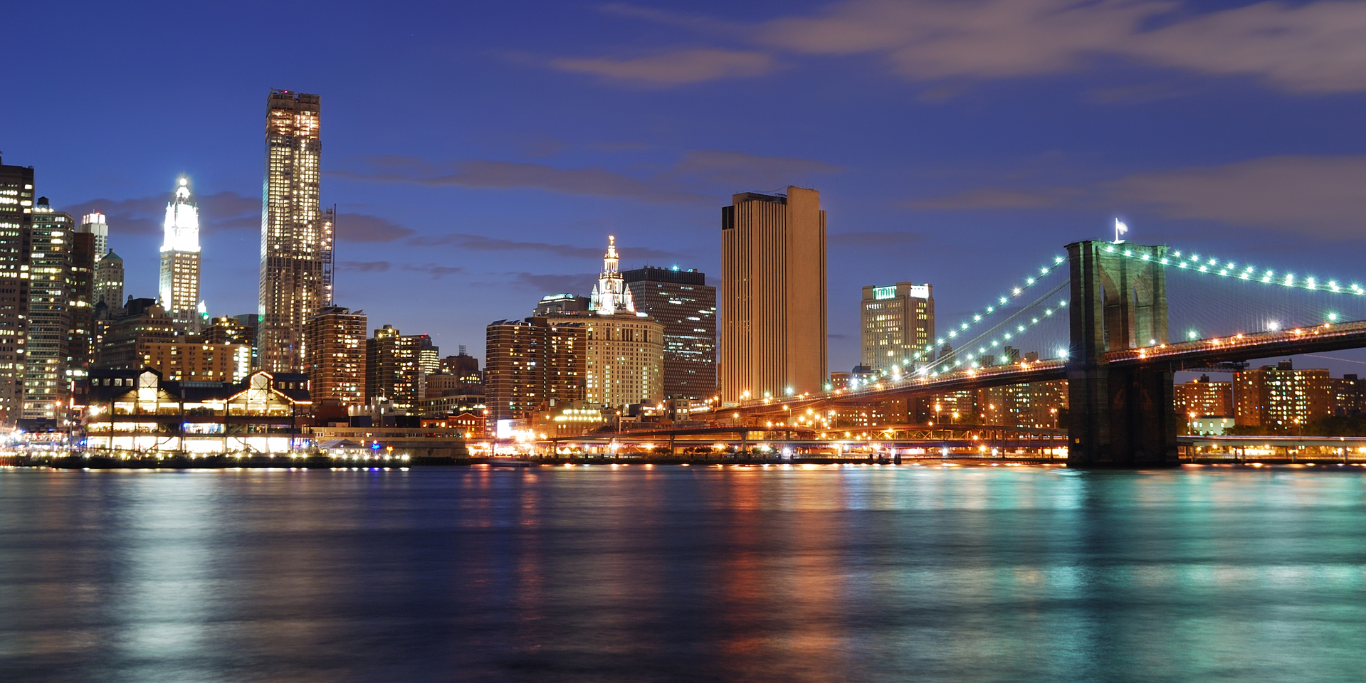 New York City Manhattan skyline and Brooklyn Bridge at dusk over Hudson River with skyscrapers