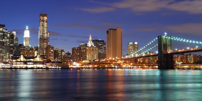New York City Manhattan skyline and Brooklyn Bridge at dusk over Hudson River with skyscrapers