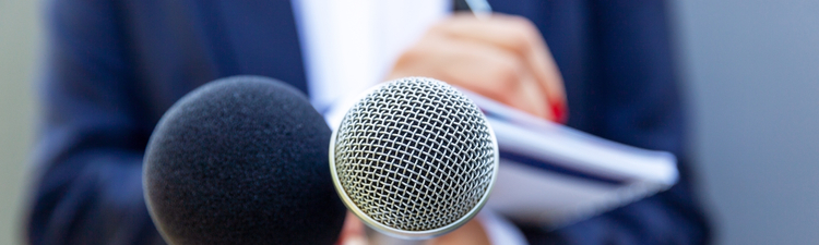 News reporter or TV journalist at press conference, holding microphone and writing notes