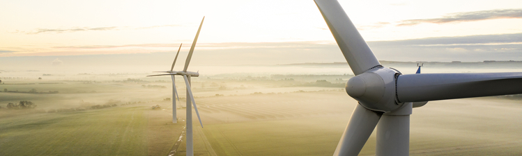 Aerial view of three wind turbines in the early morning fog at sunrise in the English countryside