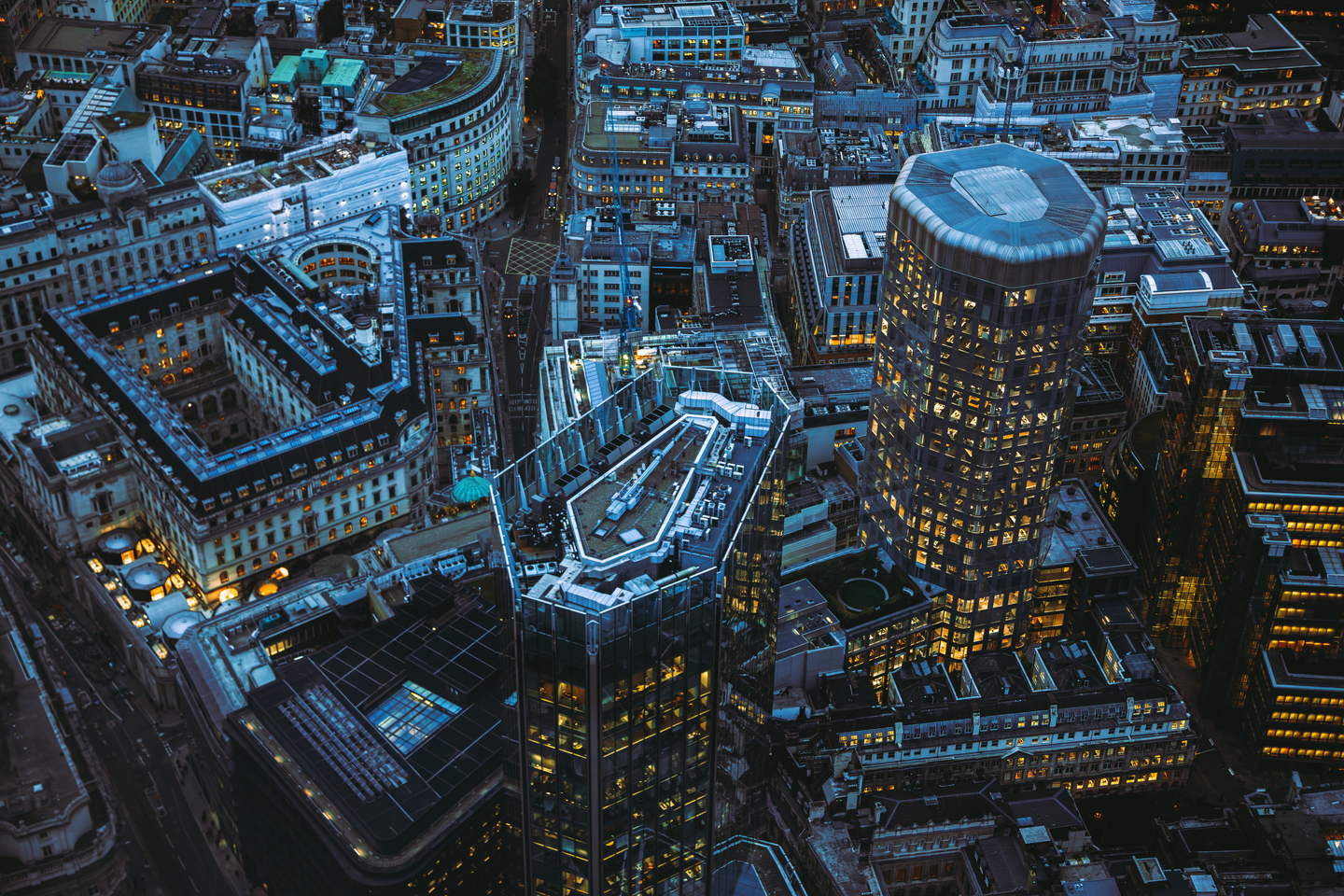 Aerial panoramic view of The City of London cityscape skyline with metropole financial district modern skyscrapers after sunset on night with illuminated buildings and cloudy sky in London, UK