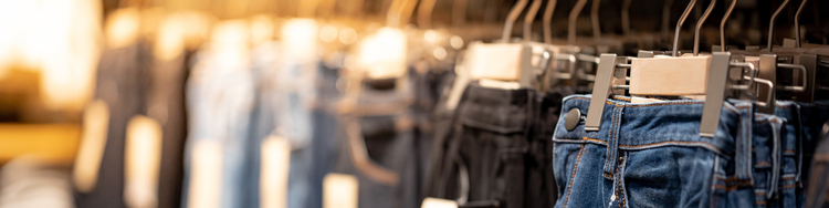 Close-up of denim jeans in varying colors hanging on clothes rack.