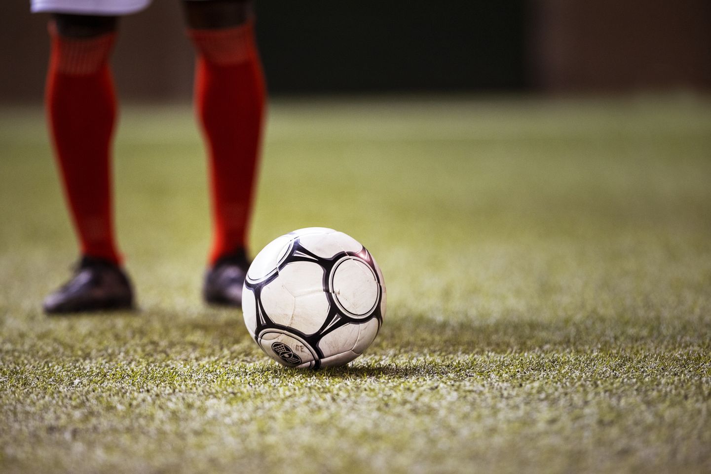 Medium angle of soccer player in red knee socks standing near soccer ball.