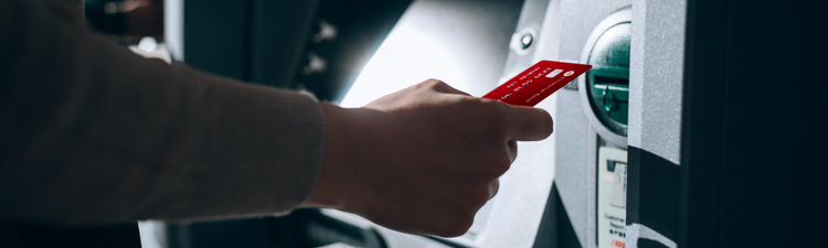 Close-up of person inserting debit card into ATM.