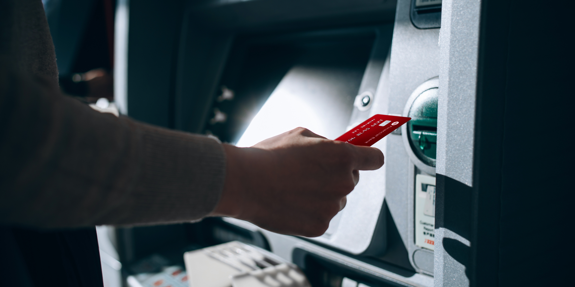 Close-up of person inserting debit card into ATM.