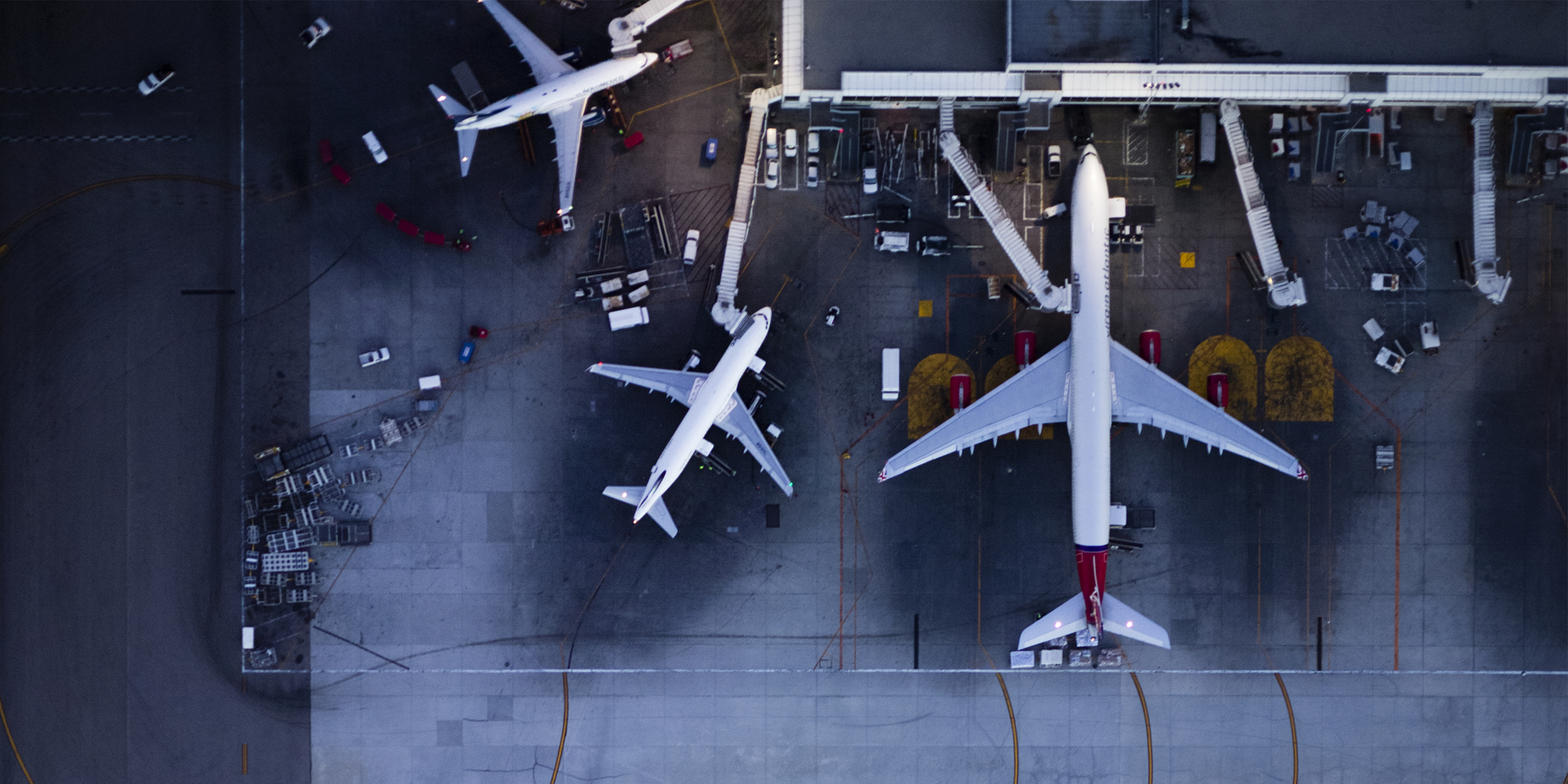 High angle down exterior shot of airplanes docking at airport terminal gates.