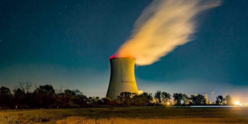Wide angle of cooling tower at nuclear power plant at night.
